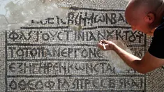 Arkeolog meneliti lantai mosaik berusia 1.500 tahun di Museum Rockefeller, Yerusalem, Rabu (23/8). Prasasti bertuliskan aksara dan bahasa Yunani kuno ditemukan selama pengerjaan pemasangan kabel komunikasi di Kota Tua Yerusalem. (AHMAD GHARABLI/AFP)