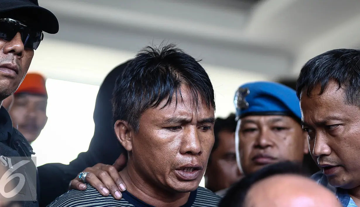 Tersangka Ridwan Sitorus alias Ius Pane (54), tiba di Bandara Halim Perdana Kusumah, Minggu (1/1). Ius menjadi tersangka atas kasus perampokan dan pembunuhan yang terjadi di rumah mewah Pulomas. (Liputan6.com/Faizal Fanani)