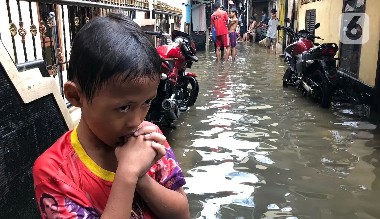 Anak-anak bermain di tengah banjir yang merendam kawasan Kebon Pala, Jakarta Timur, Selasa (25/2/2020). Akibat banjir yang tak kunjung surut, aktivitas warga di kawasan tersebut menjadi terganggu, terlebih dengan adanya pemadaman listrik. (Liputan6.com/Immanuel Antonius)