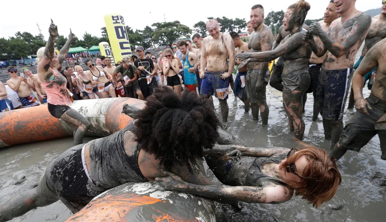 Turis mengikuti permainan dalam Festival lumpur Boryeong di Daecheon, Boryeong, Korea Selatan, (22/7). Festival yang berlangsung 21-30 Juli bertujuan untuk mendorong penggunaan lumpur sebagai kosmetik untuk perawatan kulit. (AP Photo/Ahn Young-joon)