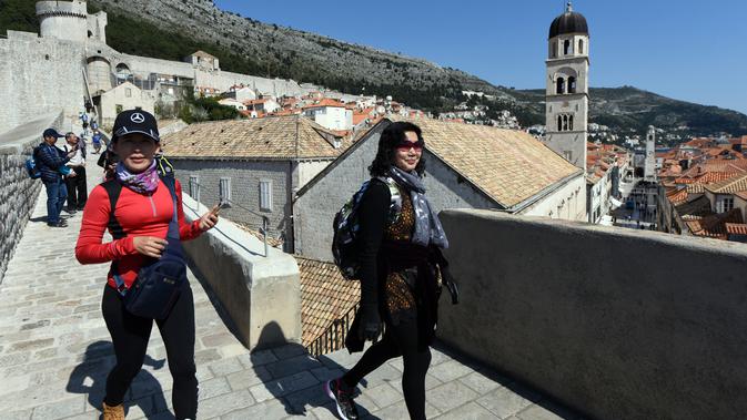 Wisatawan berjalan di atas benteng kota tua Dubrovnik pada 28 Maret 2019. Tahun lalu lebih dari 1,2 juta turis mengunjungi Dubrovnik, kota yang paling banyak dikunjungi di Kroasia. (Denis LOVROVIC / AFP)