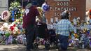 Orang-orang memberikan penghormatan dalam sebuah peringatan di luar Robb Elementary School untuk menghormati para korban yang tewas dalam penembakan di sekolah pekan ini di Uvalde, Texas, Amerika Serikat, 28 Mei 2022. (AP Photo/Dario Lopez-Mills)