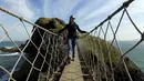 Seorang turis wanita berdiri ditengah Jembatan Carrick-a-Rede Rope di Pantai Causeway, Irlandia Utara, Rabu (8/4/2015). Jembatan unik ini memiliki panjang 19 meter dan berada di ketinggian 30 meter di atas karang laut. (REUTERS/Cathal McNaughton)