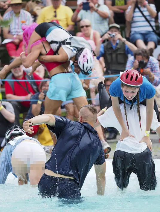 Para peserta bersaing melewati kolam sambil menggendong istrinya saat mengikuti kompetisi Wife Carrying World Championships di Sonkajarvi, Finlandia, 2 Juli 2016. Lomba unik ini digelar bulan Juli tiap tahunnya. (Timo Hartikainen/Lehtikuva/AFP)