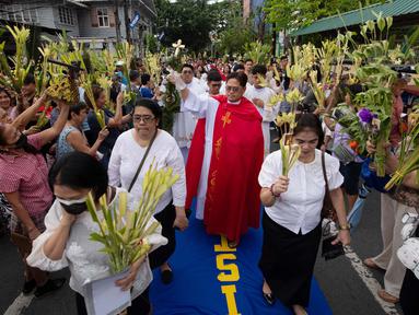 Seorang pemuka agama Katolik memberkati umat yang memegang daun palem di sepanjang jalan selama prosesi untuk menandai Minggu Palma sebagai bagian dari devosi jelang perayaan Paskah di Manila, Filipina pada 13 April 2025. (Ted ALJIBE/AFP)
