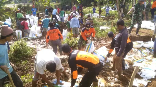 Ratusan warga dan relawan menutup titik jebolan tanggul Sungai Cibaganjing dengan karung berisi tanah. (Liputan6.com/Muhamad Ridlo)