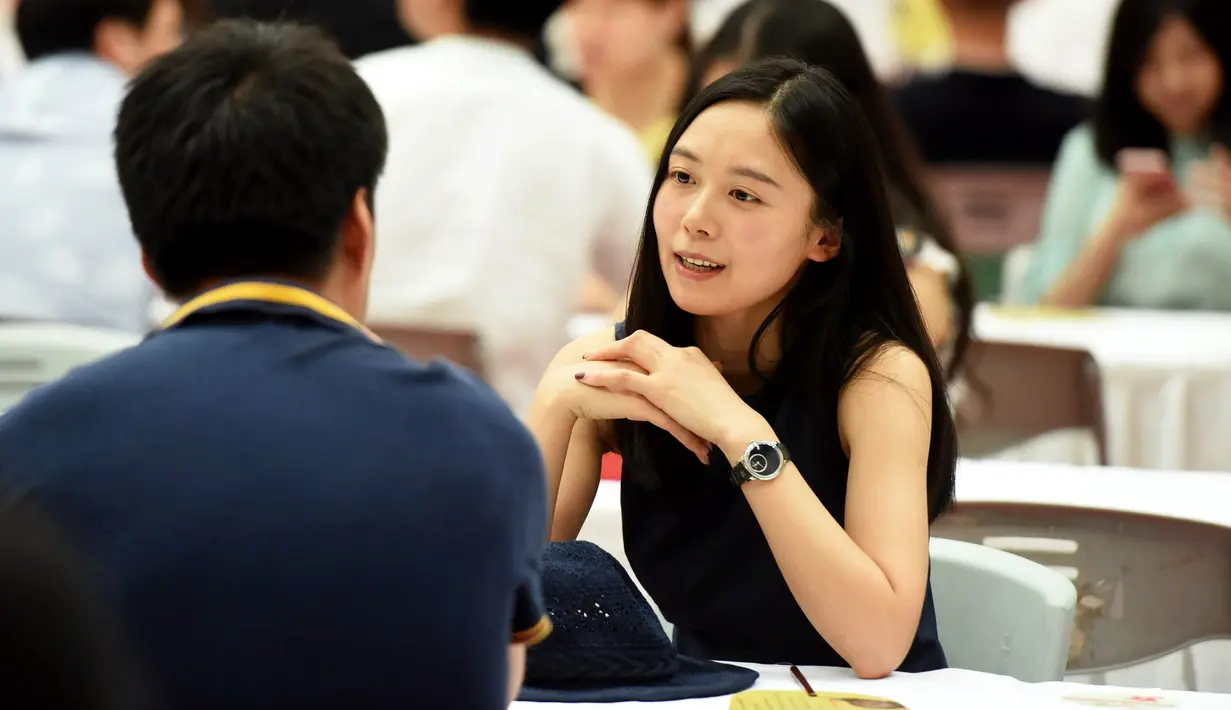 Seorang wanita berbincang dengan seorang pria saat acara perjodohan di Hangzhou, Provinsi Zhejiang, China (14/5). Acara ini menarik minat ribuan pria dan wanita. (AFP Photo/Str/China Out)