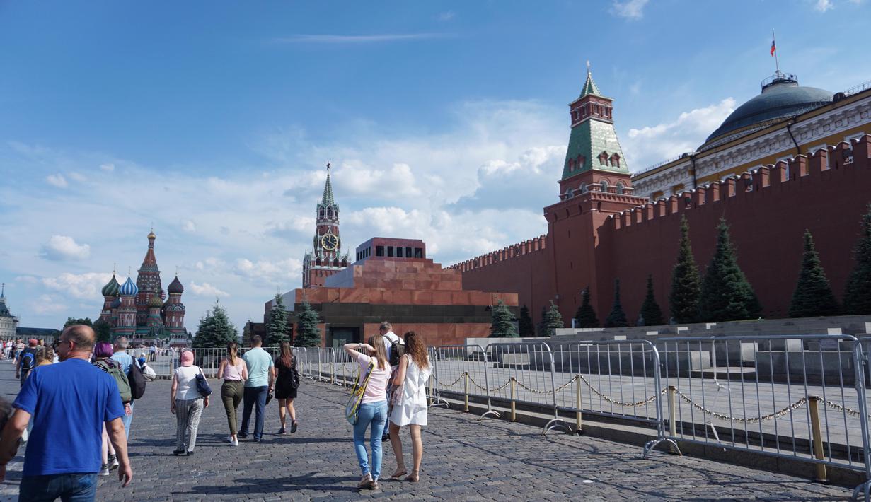 Sejumlah warga melintas di Red Square dengan tampak kanan Mauseleum Lenin dan belakang Saint Basil Cathedral. (Bola.com/Okie Prabhowo)