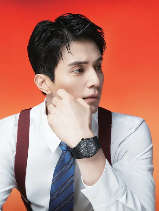Mengenakan kemeja lengan panjang putih, dipadukan dasi biru dan bralette maroon, Lee Dong Wook mengenakan jam tangan Tissot strap hitam senada dengan dialnya. [dok. Tissot]