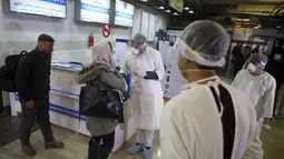 Petugas kesehatan mengenakan alat pelindung berbicara dengan penumpang dari China selama proses pengawasan wisatawan yang tiba dari China, di Bandara Internasional Hamid Karzai, Kabul, Afghanistan (3/2/2020). Jumlah korban akibat virus corona melonjak menjadi 426 orang. (AP Photo/Rahmat Gul)