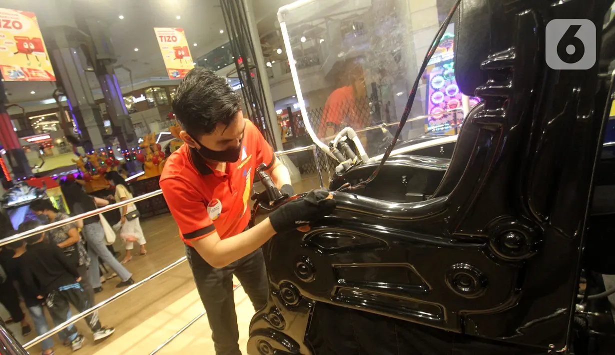 Petugas fun squad membersihkan kursi permainan di Timezone Supermal Karawaci, Tangerang, Jumat (19/11/2021). Secara berkala, funsquad selalu membersihkan dan melakukan sterilisasi mesin permainan, screening ketat, jaga jarak dan membersihkan tangan dengan hand sanitizer. (Liputan6.com/Fery Pradolo)