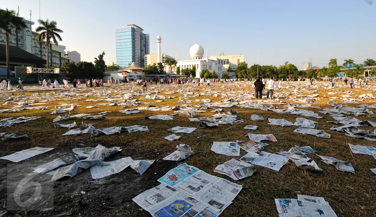 Lembaran koran bekas alas salat memenuhi lapangan Masjid Agung Al Azhar, Jakarta usai pelaksanaan salat Idul Fitri 1436 H, Jumat (17/7/2015). Sisa koran bekas akan dikumpulkan dan dimanfaatkan oleh pemulung. (Liputan6.com/Yoppy Renato)