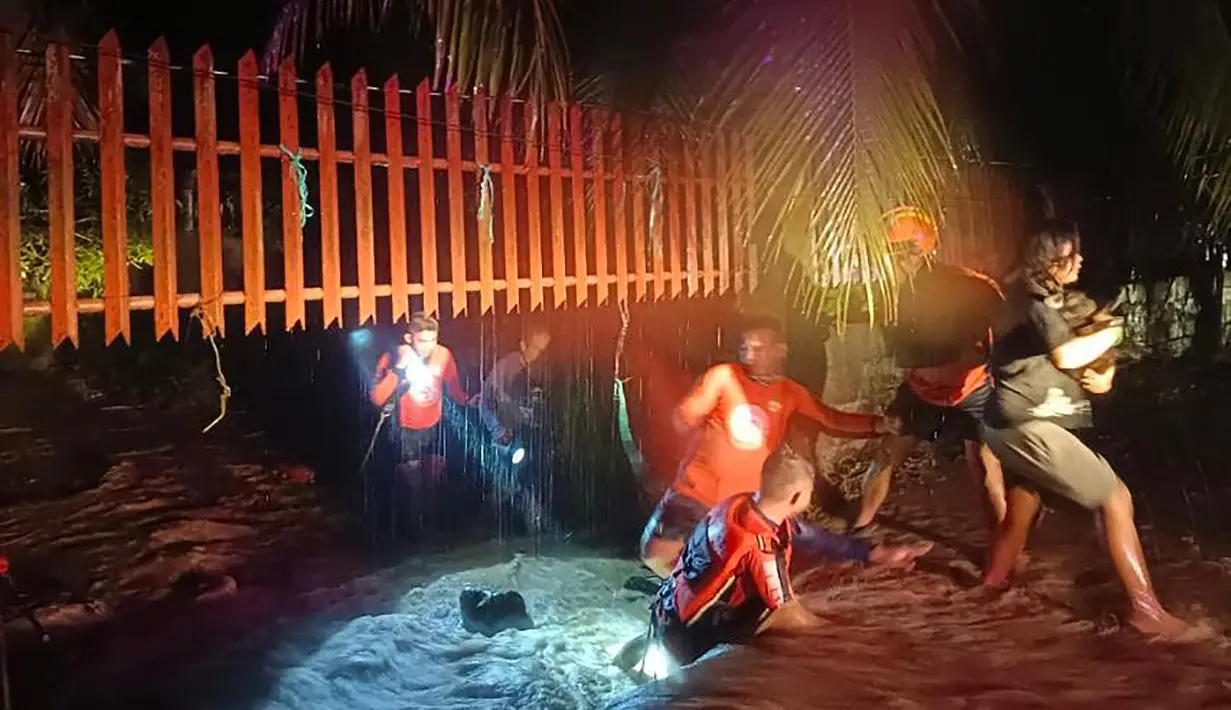 Penyelamat mengevakuasi orang-orang dari daerah banjir di Kota Ozamiz, Misamis Occidental, Filipina (25/12/2022). Dua orang tewas dan hampir 46.000 lainnya meninggalkan rumah mereka saat banjir pada libur Hari Natal. (Handout / Philippine Coast Guard (PCG) / AFP)