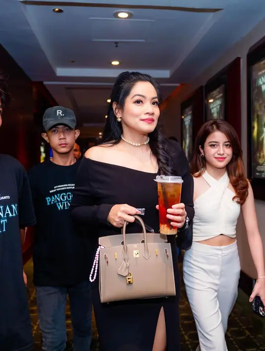 Gaun simple ini dipadukan dengan kalung choker mutiara yang klasik [@titi_kamall]