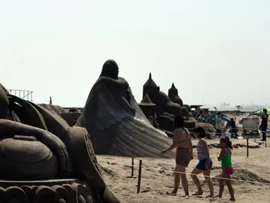 Pengunjung berjalan diantara patung pasir di pameran Asahi Sand Sculpture, Yasashigaura, pantai Asahi , Tokyo, Sabtu (11/7/2015). Pameran ini digelar mulai Senin (6/7) lalu. (AFP PHOTO/Toshifumi Kitamura)