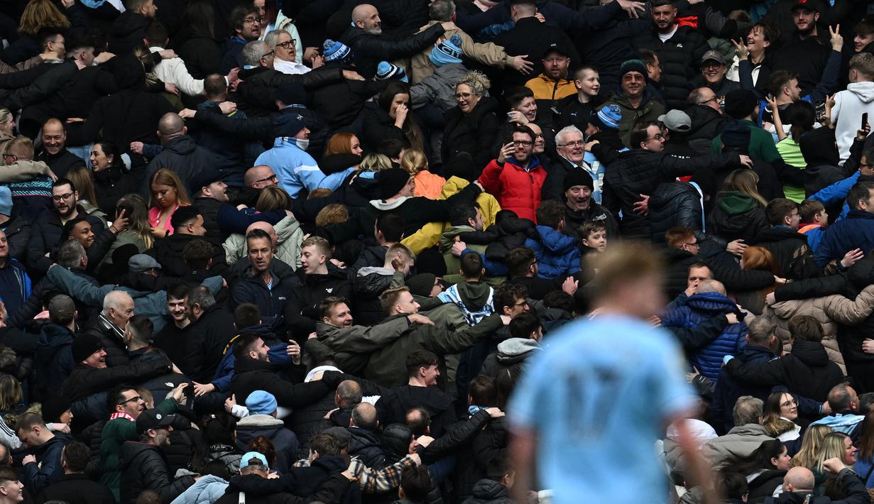 Suporter Manchester City melakukan selebrasi Poznan saat Jack Grealish mencetak gol keempat timnya ke gawang Liverpool pada laga pekan ke-29 Liga Inggris 2022/2023 yang berlangsung di Etihad Stadium, Manchester, Minggu (01/04/2023) WIB. The Cityzens menang dengan skor 4-1. (AFP/Paul Ellis)