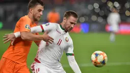 Bek Belanda, Joel Veltman, berebut bola dengan striker Belarusia, Maksim Skavysh, pada laga Kualifikasi Piala Eropa 2020 di Minsk, Minggu (13/10). Belarusia kalah 1-2 dari Belanda. (AFP/Sergei Gapon)