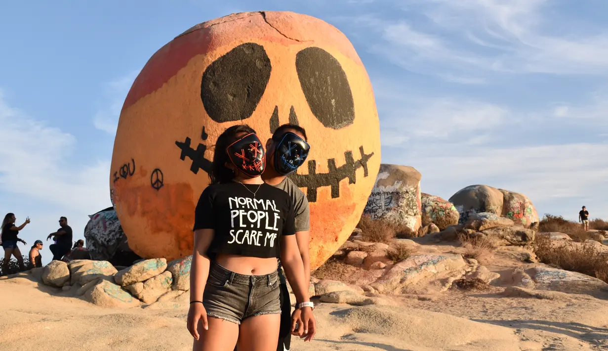 Orang-orang berpose di depan Pumpkin Rock (Batu Labu) yang berada di puncak sebuah bukit di Norco, Riverside County, California, Amerika Serikat (AS) (18/10/2020). Menjelang perayaan Halloween, Pumpkin Rock, menjadi objek wisata yang populer bagi warga setempat maupun pengunjung.  (Xinhua/Gao Shan)