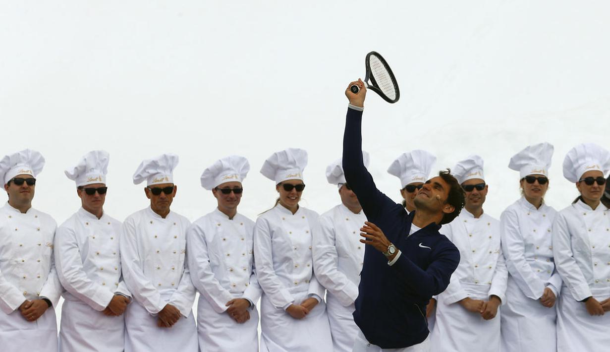 Petenis Swiss, Roger Federer, melakukan servis saat bermain tenis di ketinggian 3.475 meter melawan pemain ski AS, Lindsey Vonn, di gletser Aletsch, Jungfraujoch, (17/7/2014). (REUTERS/Denis Balibouse)