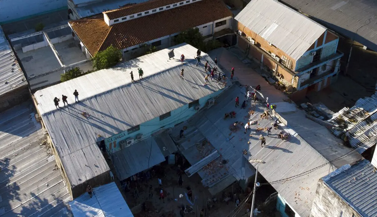 Narapidana melemparkan batu ke arah polisi dari atap penjara Tacumbu saat kerusuhan di Asuncion, Paraguay, Selasa (16/2/2021). Menurut Kementerian Kehakiman Paraguay, enam narapidana tewas dalam kerusuhan di penjara Tacumbu. (AP Photo/Jorge Saenz)