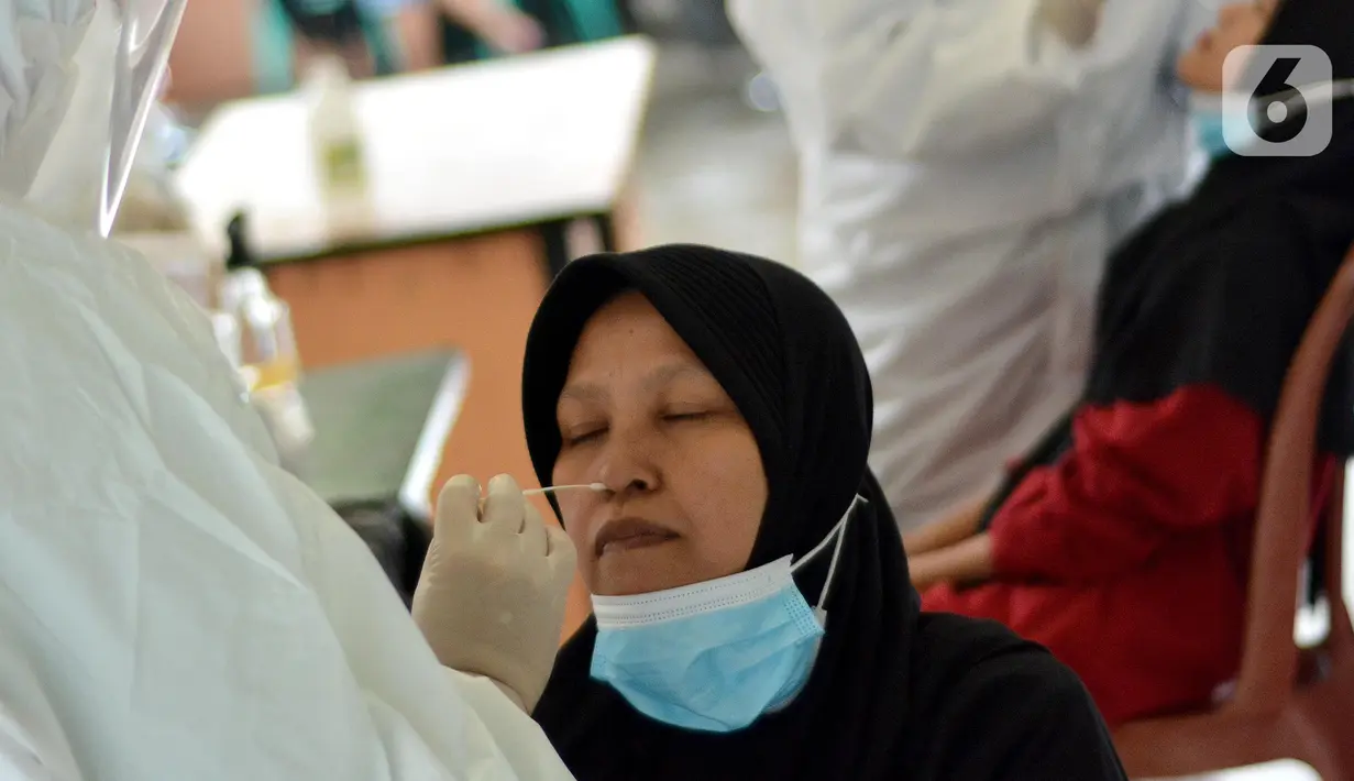 Petugas medis mengambil sampel lendir saat tes swab PCR massal di Kantor Kecamatan Pancoran Mas, Depok, Selasa (5/1/2021). Puskesmas Pancoran Mas melakukan tes Swab PCR kepada warga yang pernah memiliki riwayat kontak erat dengan pasien terkonfirmasi positif Covid-19. (merdeka.com/Arie Basuki)