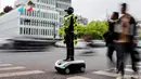 Orang-orang berjalan melewati robot polisi humanoid di Hangzhou, provinsi Zhejiang Timur, Tiongkok pada Minggu 3 Mei 2026. 15 robot humanoid dikerahkan di Hangzhou, Provinsi Zhejiang, Tiongkok. (Agatha CANTRILL/AFP)