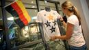 Petugas toko di Frankfurt, (14/7/2014), merapikan kaos berlogo federasi sepak bola Jerman dengan empat bintang. Tanda bintang pada kaos timnas melambangkan jumlah capaian gelar juara di ajang Piala Dunia. (AFP PHOTO/DPA/Fredrik VON Erichsen)