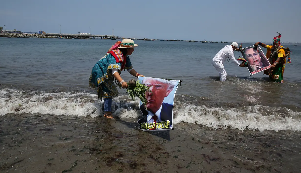 Dukun Peru membawa poster bergambar Capres AS dari Partai Demokrat, Hillary Clinton dan rivalnya dari Partai Republik, Donald Trump ke laut saat melakukan ritual prediksi menjelang pemilihan presiden AS, di Lima, Peru, Senin (7/11). (REUTERS/Mariana Bazo)