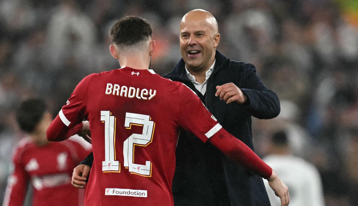 Pemain Liverpool, Conor Bradley (kiri) mendapatkan pelukan dari pelatih Arne Slot setelah berakhirnya laga Liga Champions 2025/2026 melawan Real Madrid di Anfield, Liverpool, Inggris, Selasa (04/11/2025) waktu setempat. (AFP/Paul Ellis)
