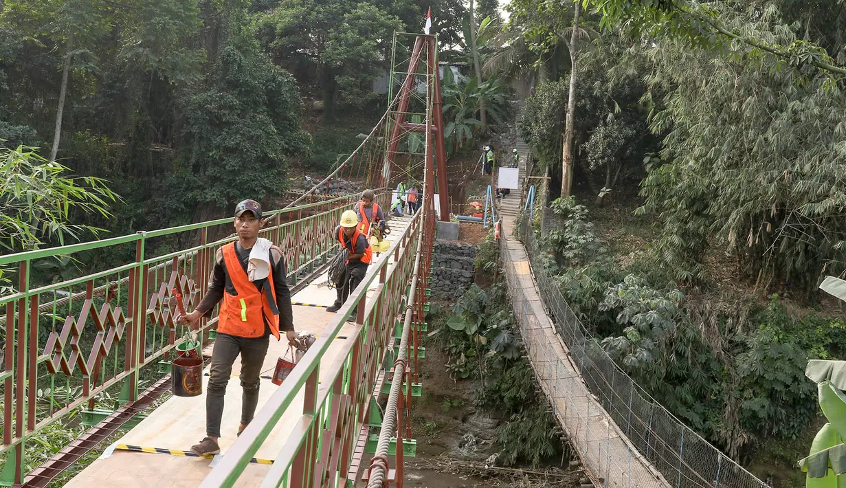 Pekerja menyelesaikan pembangunan jembatan gantung yang diberi julukan Indiana Jones di Srengseng Sawah, Jagakarsa, Jakarta, Jumat (3/8). Pemprov DKI membangun jembatan Indiana Jones karena yang lama sudah tidak layak. (Liputan6.com/Immanuel Antonius)