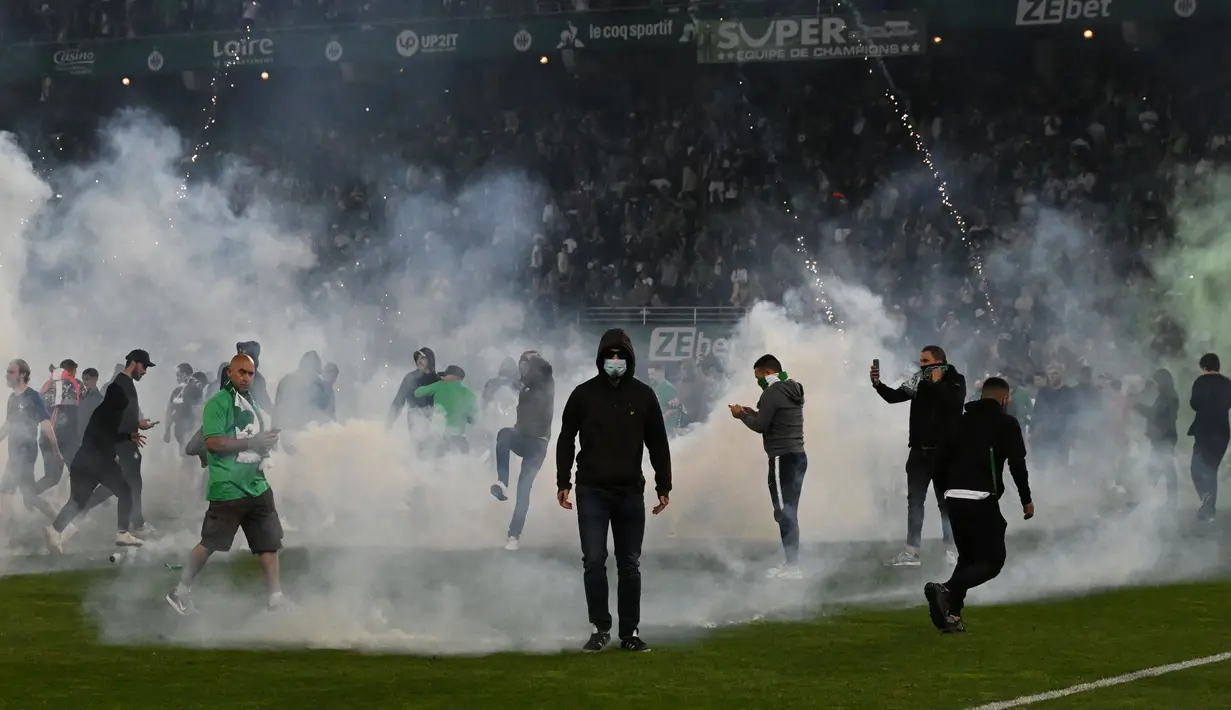Suporter Saint Etienne yang murka langsung masuk ke dalam lapangan. Situasi di Stadion Geoffrey Guichard markas Saint Etienne menjadi amat kacau dan tidak terkendali. (AFP/Jean-Philippe Ksiazek)