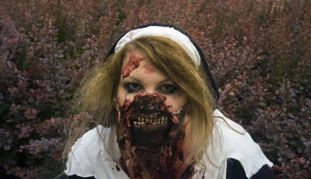 Seorang peserta wanita memamerkan hasil karyanya berupa wajah Zombie yang menyeramkan saat Parade Zombie di Praha, Ceko, Sabtu (24/05/2014) (AFP PHOTO/Michal Cizek)