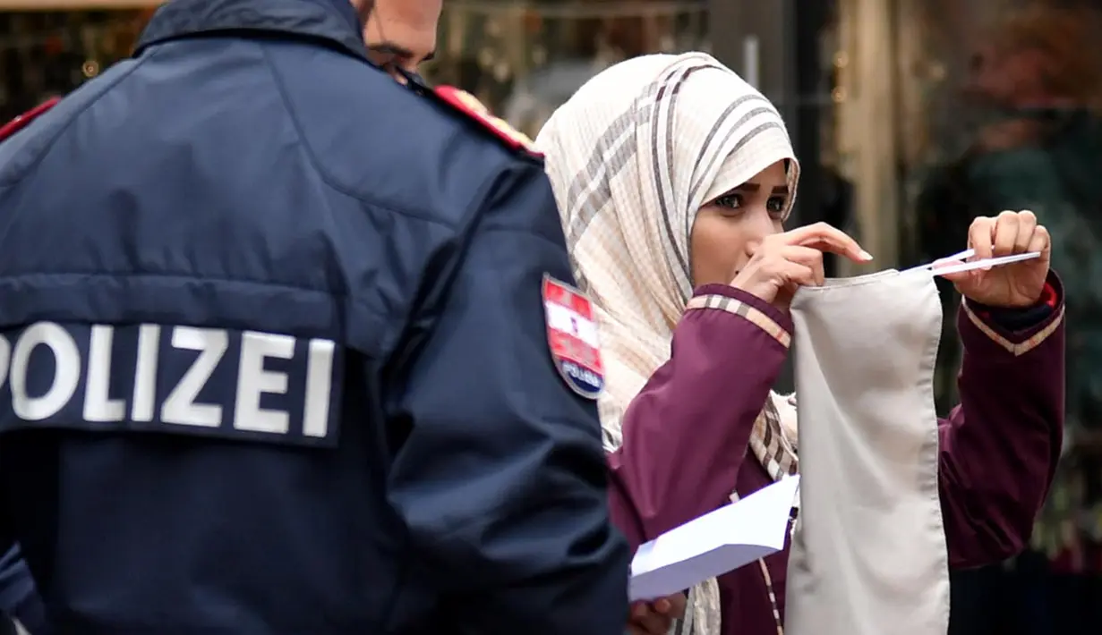 Seorang wanita Muslim dipaksa oleh polisi Austria melepaskan cadarnya saat berada di tempat umum di kota Zell am See, Minggu (1/10). Yang dilakukan polisi itu merupakan bagian dari penerapan aturan baru di negara tersebut. (BARBARA GINDL/APA/AFP)