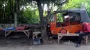 Dua orang pria melakukan aktivitas di dekat bangkai bajaj oranye di kawasan Roxy, Jakarta Barat, Selasa (27/2). Seiring berkembangnya kebutuhan transportasi yang murah dan cepat, kini bajaj oranye sudah tak lagi digunakan. (Liputan6.com/JohanTallo)