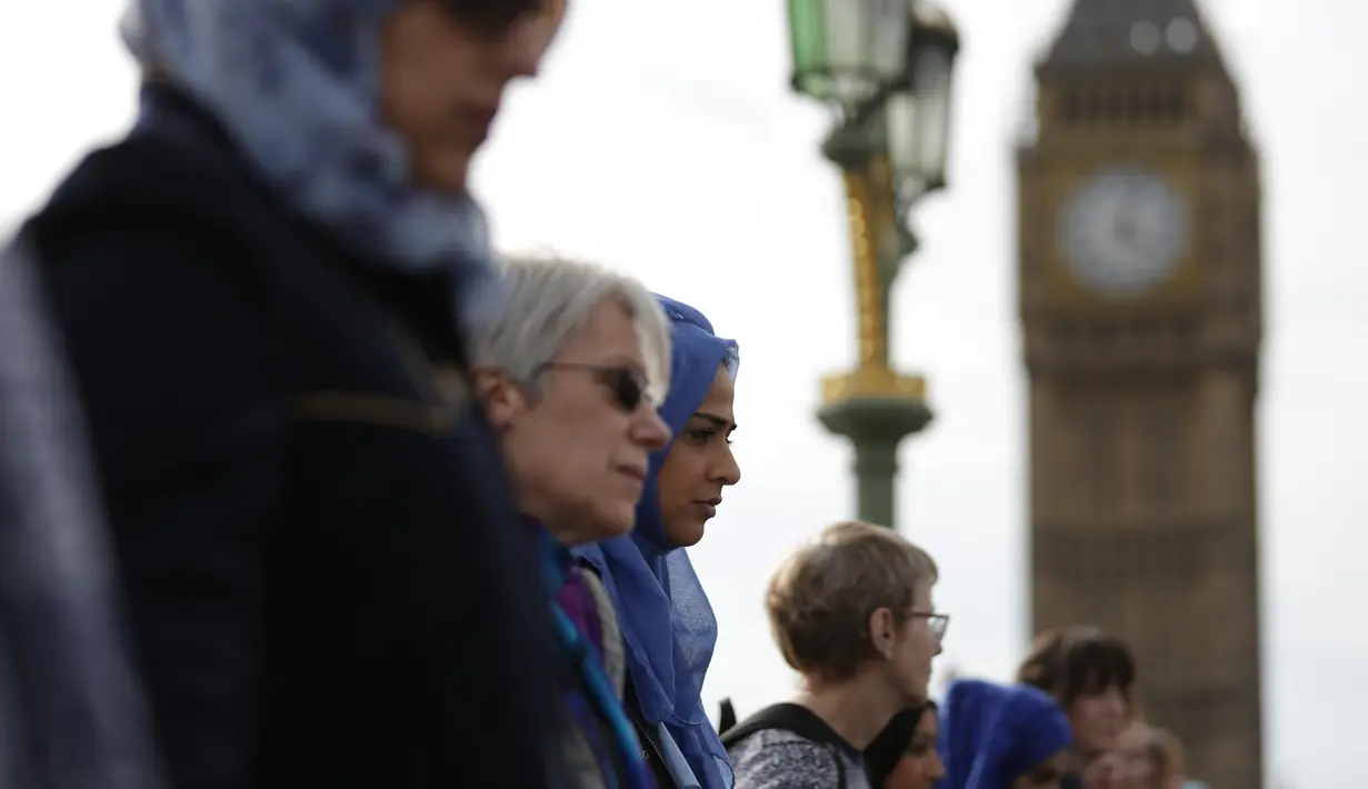 Sejumlah perempuan mengheningkan cipta di Jembatan Westminster, London, Minggu (26/3). Barisan perempuan mengenakan warna biru sebagai simbol harapan dan saling bergenggaman tangan di sepanjang jembatan tempat teror London terjadi (Daniel LEAL-OLIVAS/AFP)