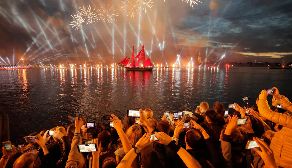 Orang-orang menonton kembang api dan perahu berlayar merah saat White Nights Festival di St.Petersburg, Rusia (24/6). Atraksi terbesar untuk memperingati White Nights adalah Alye Parusa atau Scarlet Sails (Layar Merah). (AP/Dmitri Lovetsky)