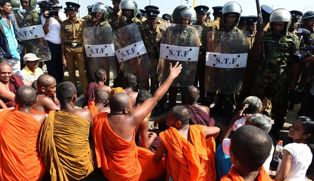 Sejumlah biksu melakukan aksi protes dengan di jaga ketat oleh petugas keamanan di kota pelabuhan selatan Hambantota, Sri Lanka (7/1). (AFP/Ishara S. Kodikara)
