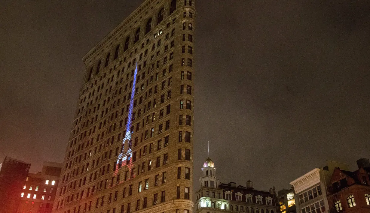 Sebuah proyeksi Menara Eiffel ditampilkan di sisi bangunan Flatiron New York City, Rabu (18/11). Gambar yang menampilkan tulisan She is tossed by waves but does not sink itu bentuk solidaritas terkait serangan teror Paris. (Andrew Burton/Getty Images/AFP)