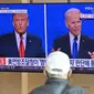 Seorang pria menonton program berita televisi tentang pemilihan presiden (pilpres) AS yang menampilkan gambar Presiden Donald Trump (kiri) dan calon presiden dari Partai Demokrat Joe Biden (kanan), di sebuah stasiun kereta api di Seoul, Korea Selatan, Rabu (4/11/2020). (Photo by Jung Yeon-je/AFP)