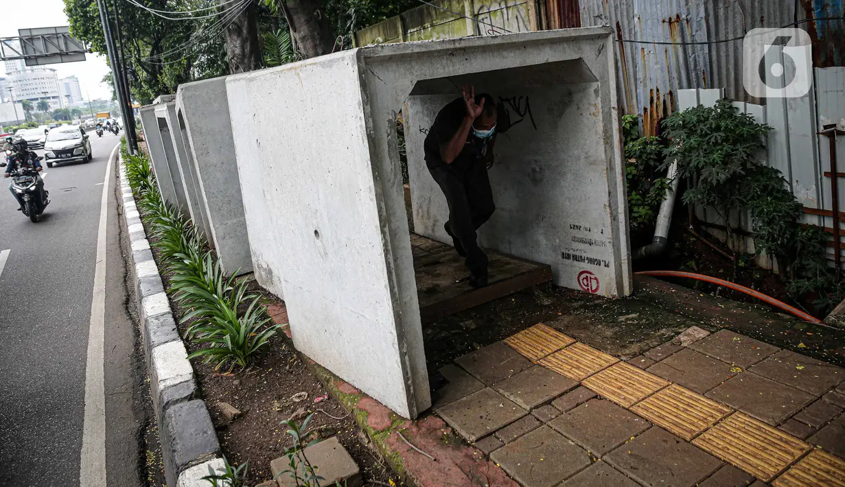 Pejalan kaki melintas di antara beton saluaran air yang berada di jalur pedestrian kawasan Gatot Subroto, Jakarta, Selasa (21/12/2021). Selain mengganggu kenyamanan, keberadaan beton saluran air tersebut juga dapat membahayakan pejalan kaki yang melintas. (Liputan6.com/Faizal Fanani)
