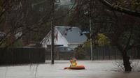 Warga menggunakan perahu kecil melintasi banjir di Christchurch, Selandia Baru, Sabtu, (22/7). Dewan Kota Christchurch mengatakan keadaan darurat setelah Sungai Heathcote meluap akibat cuaca yan buruk. (AP Photo / Mark Baker)