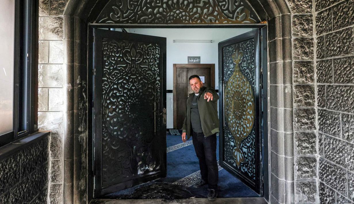 Peristiwa ini menambah daftar panjang kekerasan di Tepi Barat yang terus meningkat dalam beberapa bulan terakhir. Tampak dalam foto, seorang pria memeriksa pintu masuk Masjid Abu Bakr al-Siddiq di desa Tell, sebelah barat Nablus, Tepi Barat yang diduduki, pada 23 Februari 2026. (JAAFAR ASHTIYEH/AFP)