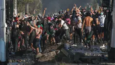 Demonstran saat bentrok dengan polisi di tengah pandemi virus corona Covid-19 selama penguncian wilayah (lockdown) di lingkungan miskin di Santiago, Chili, (18/5/2020). Mereka  protes menuntut bantuan makanan dari pemerintah. (AP Photo/Esteban Felix)