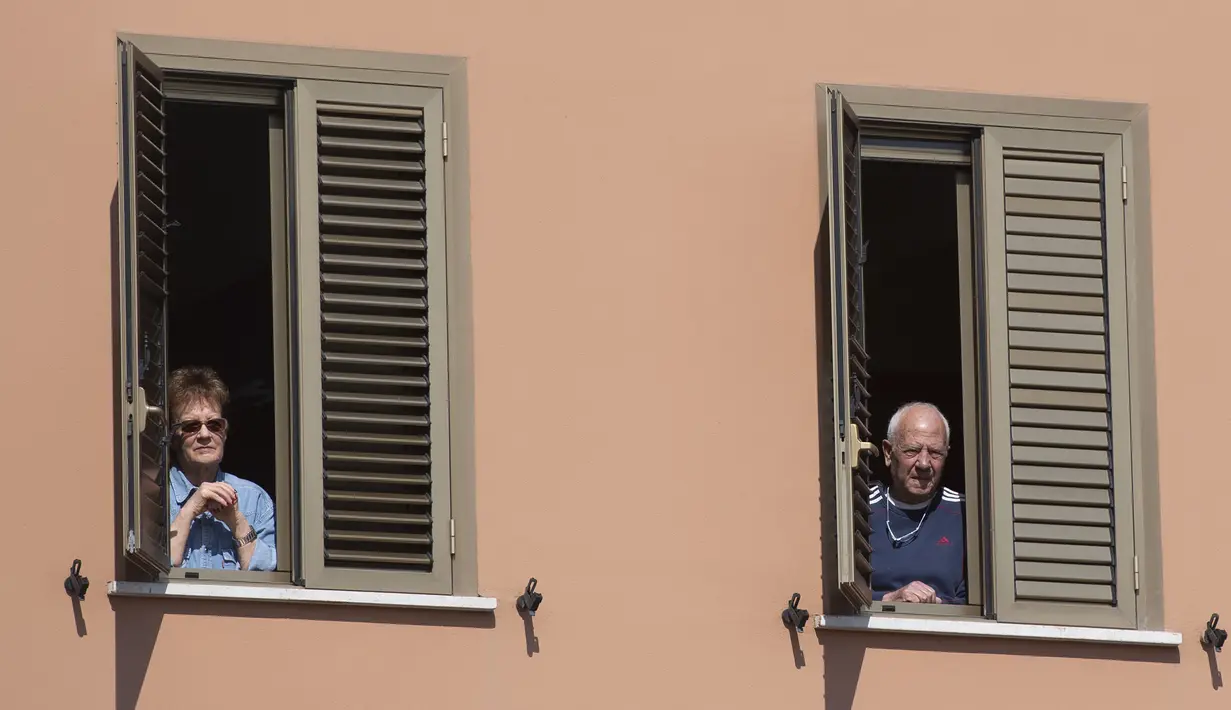 Penghuni apartemen menyaksikan perayaan Minggu Palma di Roma, Italia, 5 April 2020. Menurut Departemen Perlindungan Sipil Italia pada 6 April 2020, jumlah kasus virus corona COVID-19 di negara tersebut menjadi 132.547 infeksi, 16.523 meninggal, dan 22.837 sembuh. (Tiziana FABI/AFP)