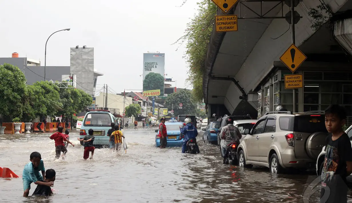 Sejumlah anak-anak tampak asyik bermain di air banjir yang merendam Jalan Matraman, Jakarta Timur. (Liputan6.com/Miftahul Hayat)