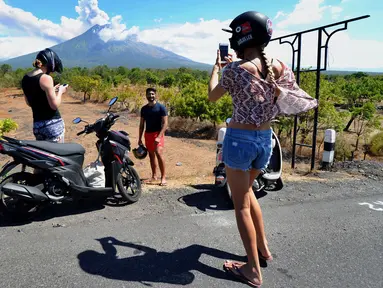 Sejumlah turis mengabadikan pemandangan erupsi Gunung Agung di Kabupaten Karangasem, Bali, Jumat (6/7). Erupsi Gunung Agung mengundang banyak perhatian warga dan wisatawan. (AFP FOTO / Sonny Tumbelaka)