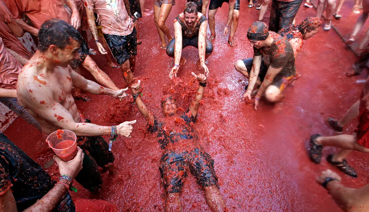 Seorang pria tergeletak digenangan tomat saat festival La Tomatina berlangsung di desa Bunol, Spanyol, Rabu (30/8). Peserta dibanderol sebesar 12 dollar atau 160 ribu rupiah untuk mengikuti rangkaian festival tersebut. (Alberto Saiz/AP)