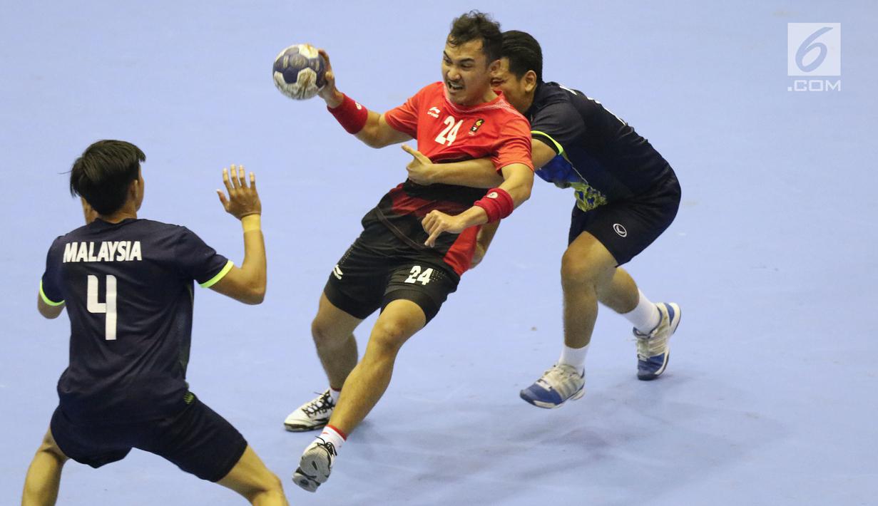 Pemain bola tangan Indonesia, Dupa Gilang Pratama W (tengah) mencoba lolos dari kawalan pemain Malaysia pada penyisihan grup 3 bola tangan Asian Games 2018 di GOR PP POPKI, Jakarta, Minggu (26/8). Indonesia unggul 31-22. (Liputan6.com/Helmi Fithriansyah)