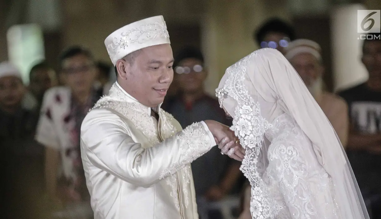 Angel Lelga mencium tangan Vicky Prasetyo saat akad nikah di Mesjid Istiqlal, Jakarta, Jumat (9/2). Kebahagiaan tecermin dari wajah pasangan ini setelah dinyatakan sah sebagai suami istri oleh para saksi. (Liputan6.com/Faizal Fanani)