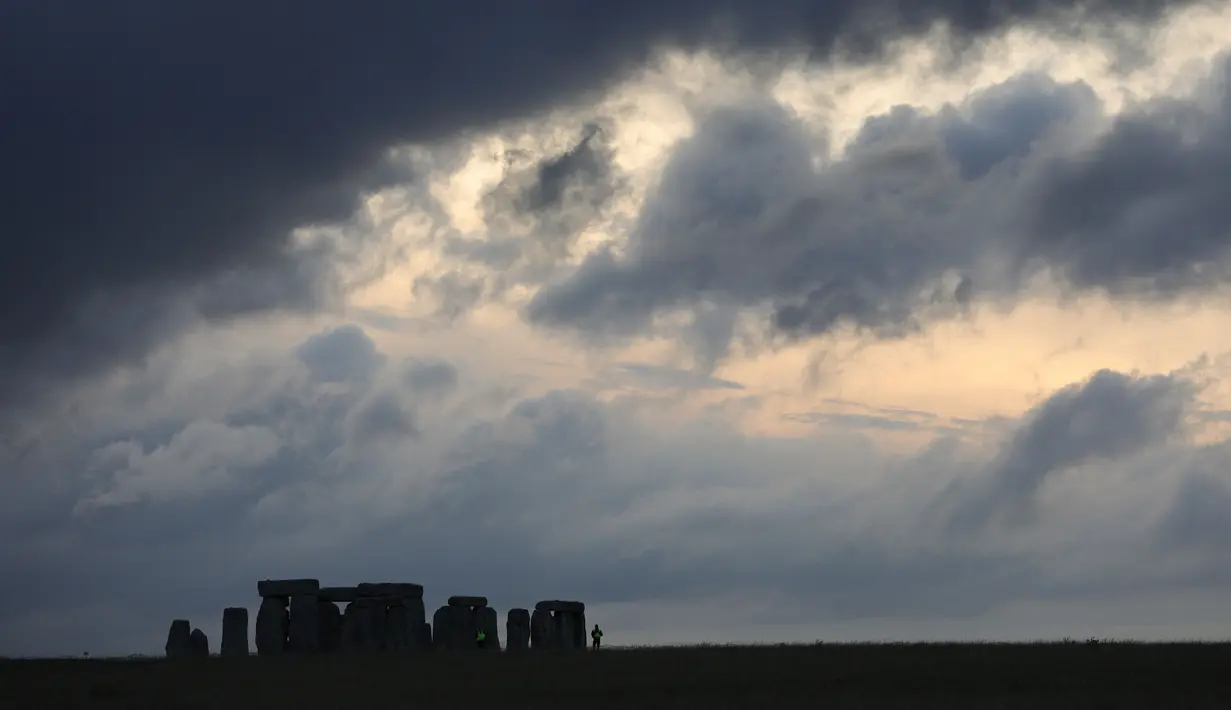 Foto yang diabadikan 20 Juni 2020 menunjukkan matahari terbenam dan para petugas keamanan berpatroli di situs warisan dunia Stonehenge di Wiltshire, Inggris. Sebuah lingkaran yang terdiri dari lubang-lubang prasejarah yang dalam ditemukan di dekat situs warisan dunia tersebut. (Xinhua/Tim Ireland)